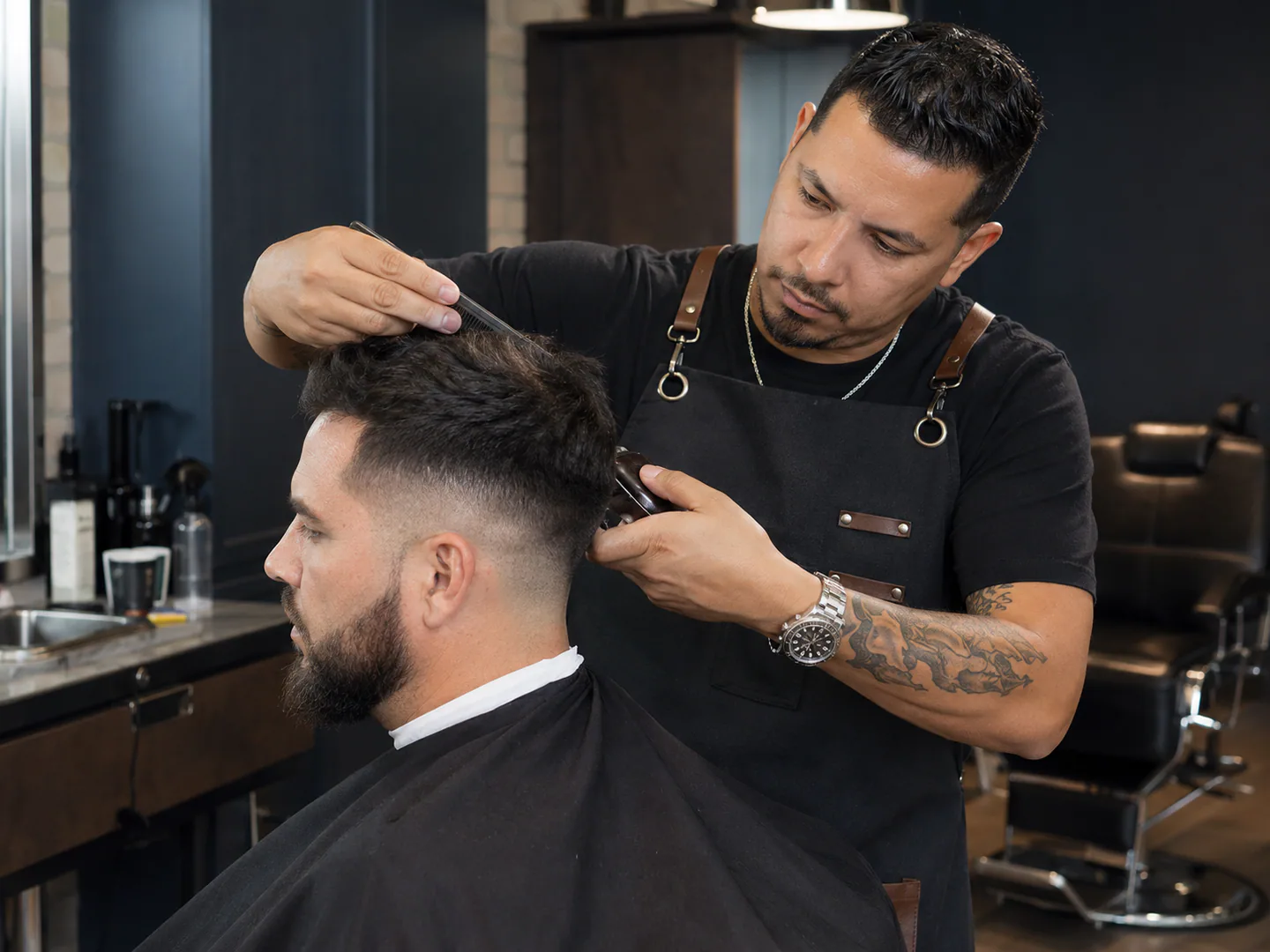 Barber actively serving a client in a polished inclusive shop