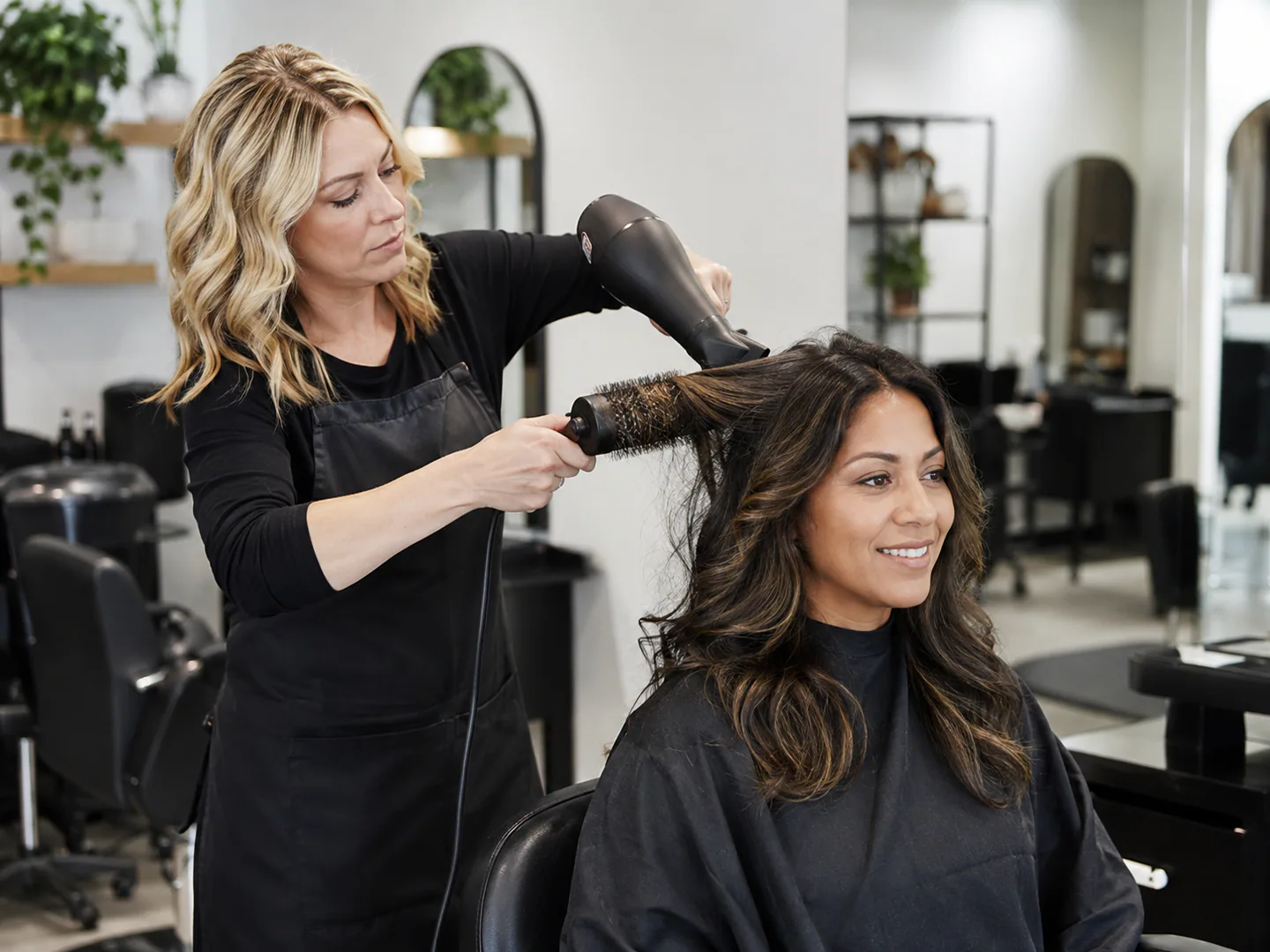 Hair stylist actively serving a client in a bright professional salon